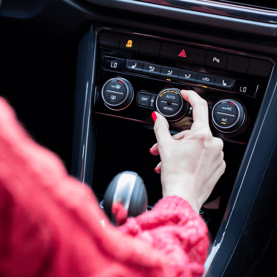 Air-con Care Packages A lady in the driver's seat of a Volkswagen vehicle configuring the air conditioning console of the vehicle.