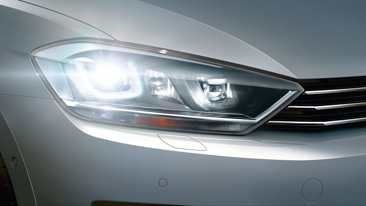 Lighting systems | Dynamic cornering lights A close-up look of a silver Volkswagen vehicle with its Bi-Xenon headlights switched on.