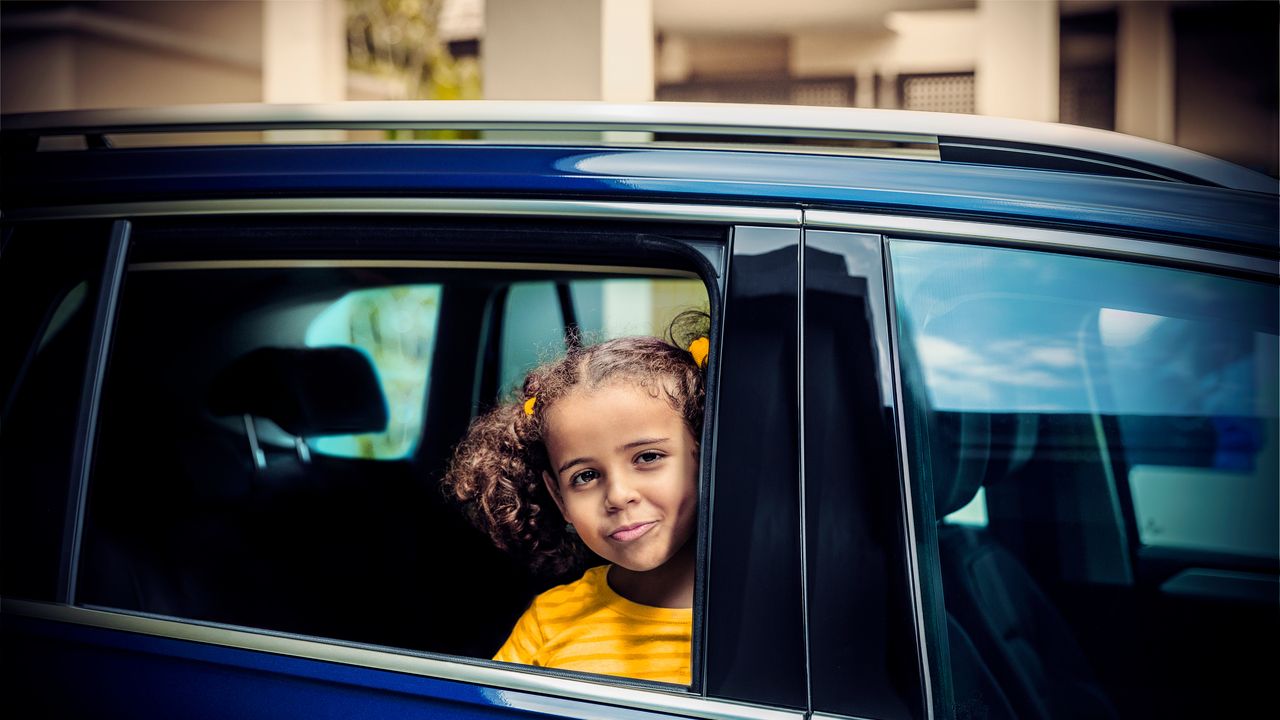 Child safety A child in a blue Volkswagen SUV looking out of the passenger window.