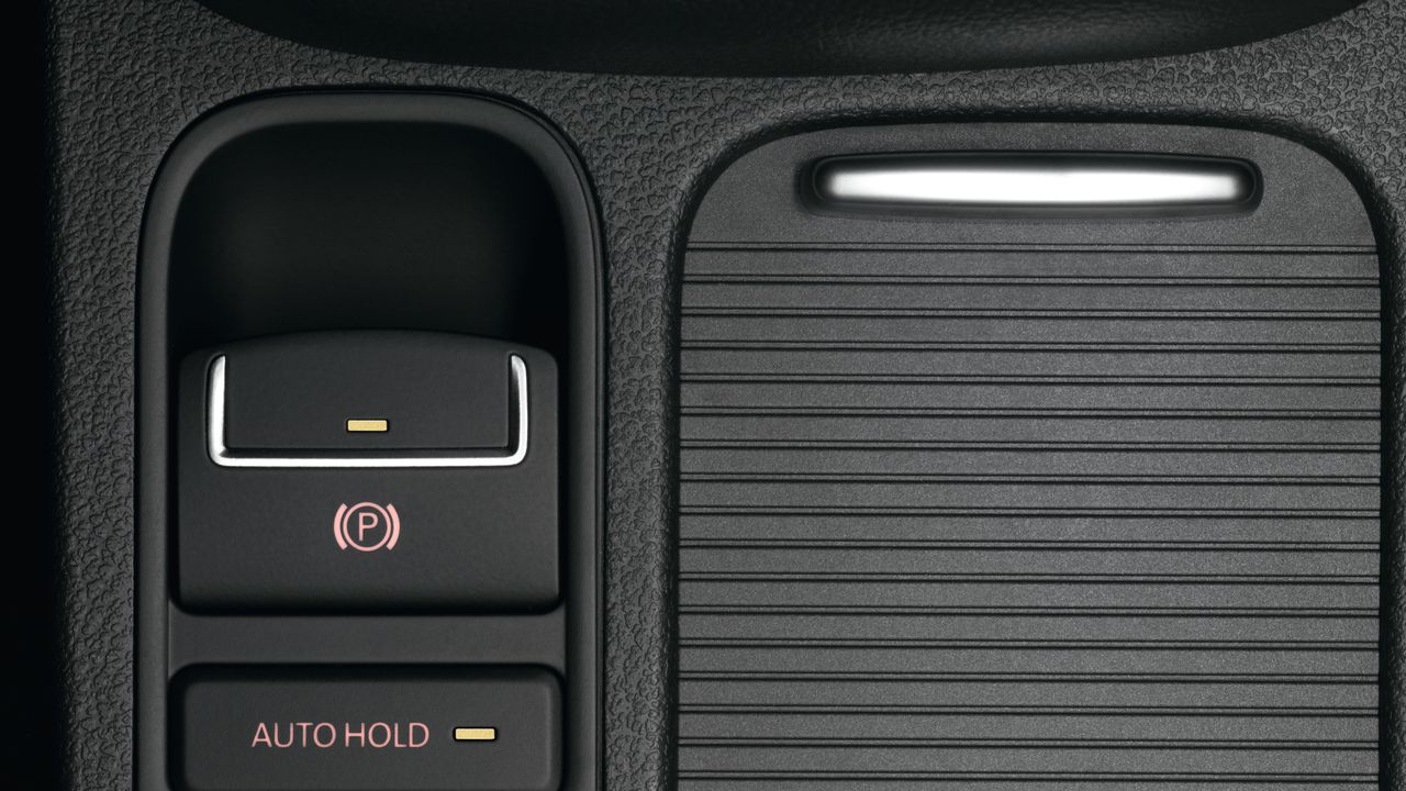 Electronic parking brake A close up look featuring the electronic parking brake and Auto Hold being switched on for a Volkswagen vehicle at its central console area.